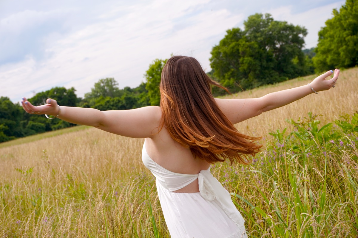 Cara Paige with arms outstretched in a golden field