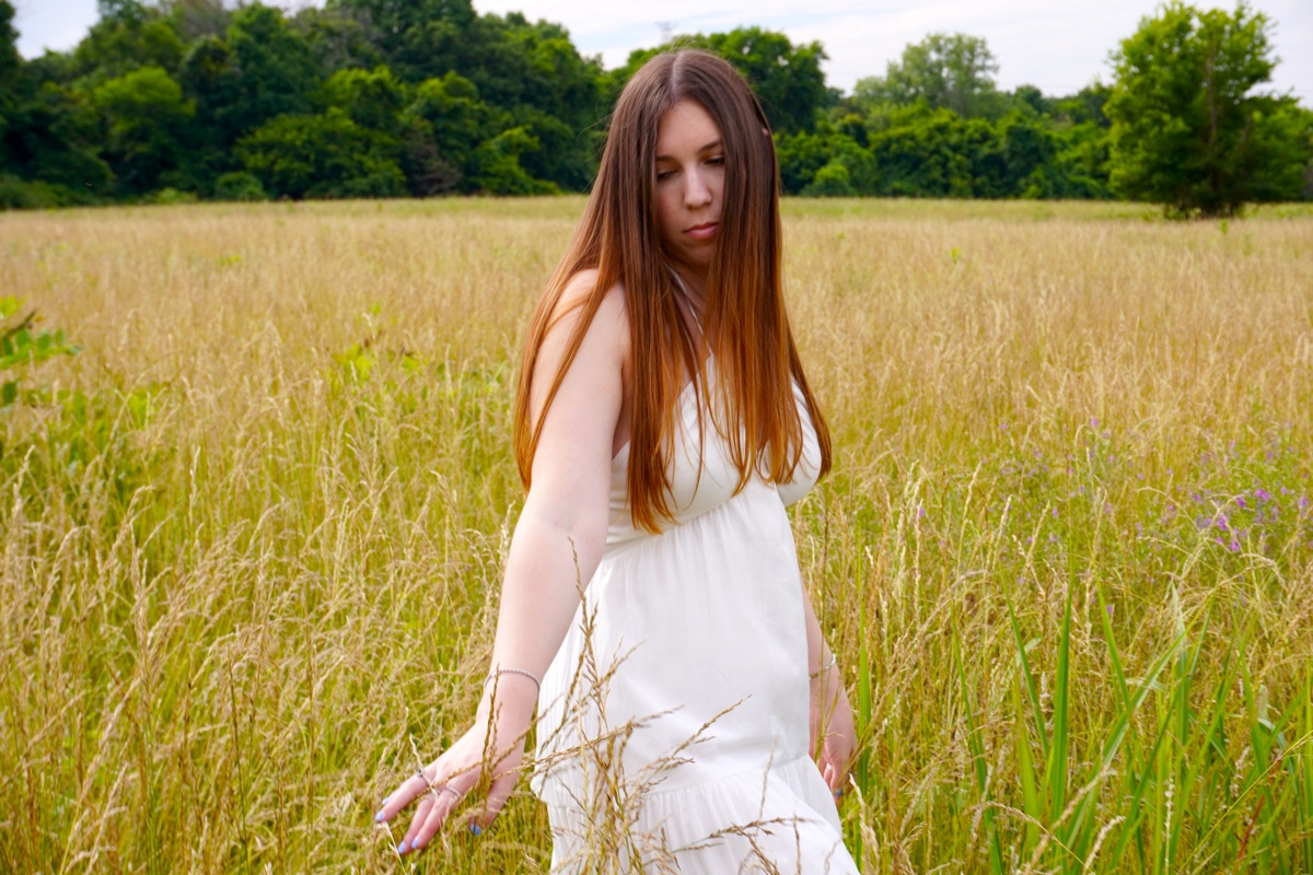 Cara Paige with arms outstretched in a field